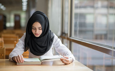 Student reading a book at a quiet study table, representing study habits at AlminarAcademy